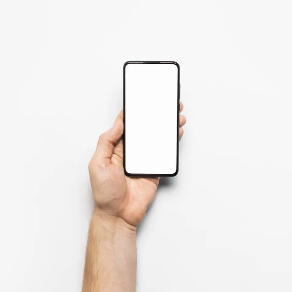 Erkek eller açık gri arka planda beyaz beyaz ekranlı modern bir siyah akıllı telefon tutuyor. Modern teknoloji, telefon, cihazlar, dokunmatik ekran, tasarımınız için şablon. Model