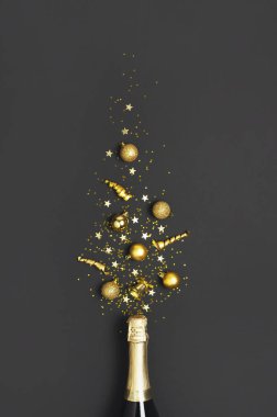 Noel ve Yeni Yıl geçmişi. Şampanya şişesi, altın noel baloları, şenlikli kurdeleler, siyah arka plan manzaralı yıldız konfetileri. Tatil kartı. Parti konsepti Festivalsel dekorasyonlar 2020