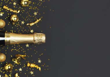 Noel ve Yeni Yıl geçmişi. Şampanya şişesi, altın noel baloları, şenlikli kurdeleler, siyah arka plan manzaralı yıldız konfetileri. Tatil kartı. Parti konsepti Festivalsel dekorasyonlar 2020