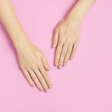 Güzel, zarif bir manikür. Pembe arka planda, düz manzaralı genç bir kadının elleri fotokopi çekiyordu. Doğal oje, jöle, kişisel bakım, güzellik ve moda. Tırnak bakımı, güzellik salonu reklamı.