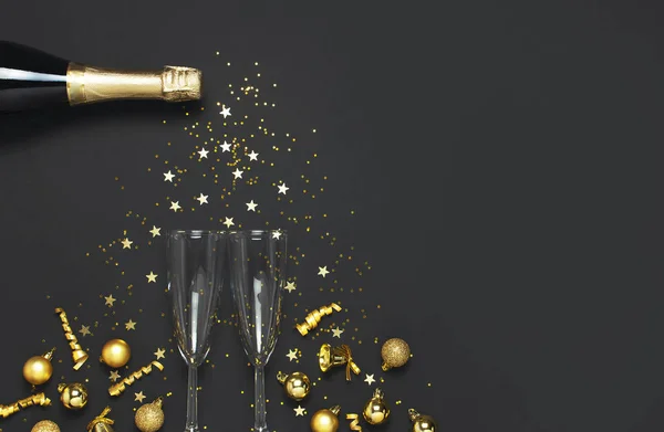 Noel ve Yeni Yıl geçmişi. Şampanya şişesi şampanya bardakları altın noel baloları şenlik kurdeleleri yıldız konfetileri siyah arka plan manzaralı. Tatil kartı. Parti dekorasyonları 2020