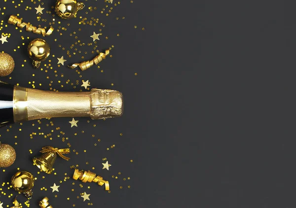 Natale e Capodanno sfondo. Bottiglia di champagne, palline di Natale dorate, nastri festivi, coriandoli stellati su sfondo nero vista dall'alto. Biglietto per vacanze flat lay. Concetto di festa Decorazioni festive 2020 — Foto Stock