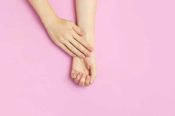 Snygg vacker mild manikyr. Händerna på ung kvinna på rosa bakgrund ovanifrån platt låg kopia utrymme. Naturliga naglar, gellack, egenvård, skönhet och mode. Nagelvård, Skönhetssalong reklam — Stockfoto