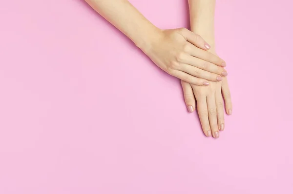 Snygg vacker mild manikyr. Händerna på ung kvinna på rosa bakgrund ovanifrån platt låg kopia utrymme. Naturliga naglar, gellack, egenvård, skönhet och mode. Nagelvård, Skönhetssalong reklam — Stockfoto