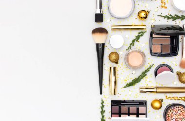 Makyaj maskarası vakfı krem ruj göz farı göz farı, yeni yıl süslemeleri altın noel topları konfeti yıldızları düz zemin üzerinde köknar dalları. Kozmetik, Noel Xmas