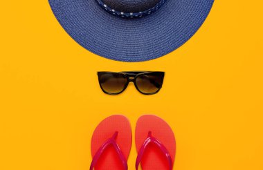 Yaz plaj deniz aksesuarları. Mercan parmak arası terlik, mavi hasır şapka, güneş gözlüğü, kabukları, sarı arka plan üst görünüm düz üzerinde denizyıldızı kopyalama alanı yatıyordu. Yaz geçmişi. Tatil tatil seyahat konsepti