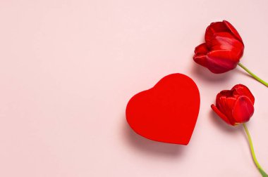 Kırmızı laleler, kırmızı kalp şeklinde hediye kutusu, pastel pembe arka plan üst görünüm Düz metin üzerinde konfeti kopyalama alanı yatıyordu. Anneler Günü, Sevgililer Günü, doğum günü, tatil geçmişi. Bahar çiçekleri, Lovely tebrik kartı
