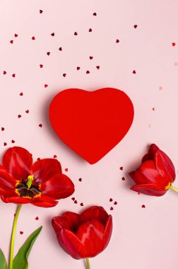 Kırmızı laleler, kırmızı kalp şeklinde hediye kutusu, pastel pembe arka plan üst görünüm Düz metin üzerinde konfeti kopyalama alanı yatıyordu. Anneler Günü, Sevgililer Günü, doğum günü, tatil geçmişi. Bahar çiçekleri, Lovely tebrik kartı