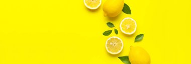 Taze limonlar ve parlak sarı arka planda yeşil yapraklarla yaratıcı bir altyapı. Üst görünüm düz kopya alanı. Limonlu turunçgiller minimum C vitamini bileşimi, limon dilimleriyle.