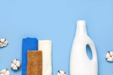 Çamaşır deterjanının beyaz plastik ambalajı, sıvı toz, çamaşır deterjanı, havlular ve mavi arka planda pamuk çiçekleri. Düz görünüm kopyalama alanı yatıyordu. Biyolojik organik ürün. Çevre temizleme kavramı