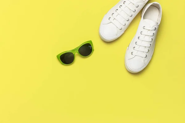 Białe damskie sneakers mody, modne okulary przeciwsłoneczne, biały T-shirt na żółtym tle. Płaski lay góry widok przestrzeni kopiowania. Obuwie damskie, akcesoria. Stylowe, białe tenisówki. Kreatywna koncepcja blog Fashion — Zdjęcie stockowe