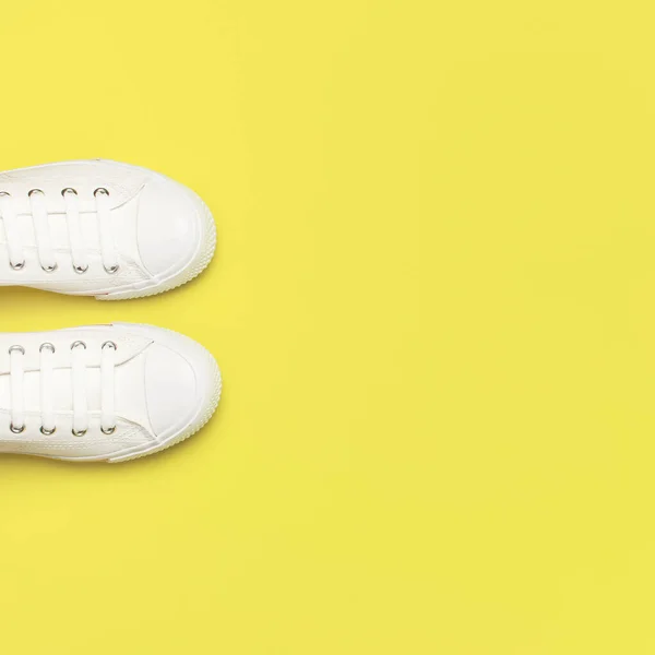 Білі кросівки жіночої моди на жовтому тлі. Плоский простір копіювання зверху. Жіноче взуття. Стильні білі кросівки. Модний блог або концепція журналу. Мінімалістичний фон взуття, спорт — стокове фото