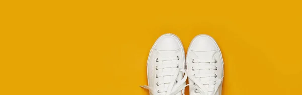 Witte vrouwelijke mode sneakers op geel oranje achtergrond. Platte lay Top View Kopieer ruimte. Damesschoenen. Stijlvolle witte sneakers. Mode blog of magazine concept. Minimalistische schoen achtergrond, sport — Stockfoto