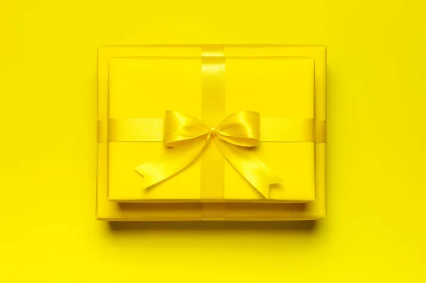 两个明亮的黄色礼品盒，黄色背景上有彩带和蝴蝶结的顶视图复制空间。平铺假日背景.生日礼物，三月八日，母亲节，情人节。祝贺你 — 图库照片