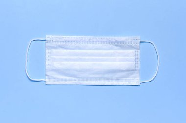 Mavi arka plandaki tıbbi maske, fotokopi alanının üst görüntüsüydü. Virüse karşı koruma, koronavirüs, grip, soğuk algınlığı, hastalıklar. Geleneksel tıbbi araç, sağlık kavramı. Tıbbi geçmiş