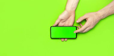 Erkek eller, neon yeşil arka plan düz manzaralı yeşil ekranlı modern siyah akıllı telefonu tutarlar. Modern teknoloji, telefon, cihazlar, dokunmatik ekran, tasarımınız için şablon. Model