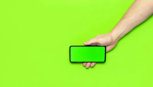 Erkek eller, neon yeşil arka plan düz manzaralı yeşil ekranlı modern siyah akıllı telefonu tutarlar. Modern teknoloji, telefon, cihazlar, dokunmatik ekran, tasarımınız için şablon. Model — Stok fotoğraf