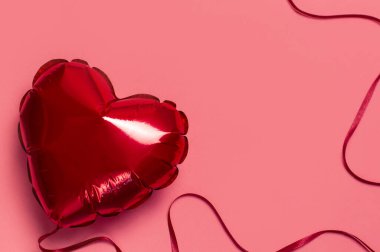 Aşk konsepti. Pembe zemin arkaplanda kalp şeklinde kırmızı balon düz fotokopi alanı uzanıyor. Tatil Nesnesi, Doğum günü, Sevgililer Günü, Düğün. Parti dekorasyonu. Tebrik kartı