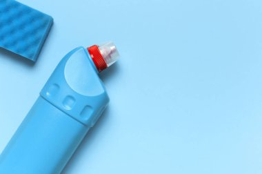 Sıvı deterjan, temizlik maddesi, çamaşır suyu, antibakteriyel jel ve mavi arka planda yıkama süngeri için mavi plastik şişe. Ev temizliği konsepti. Düz manzaralı. Aksesuarlar temizleniyor.
