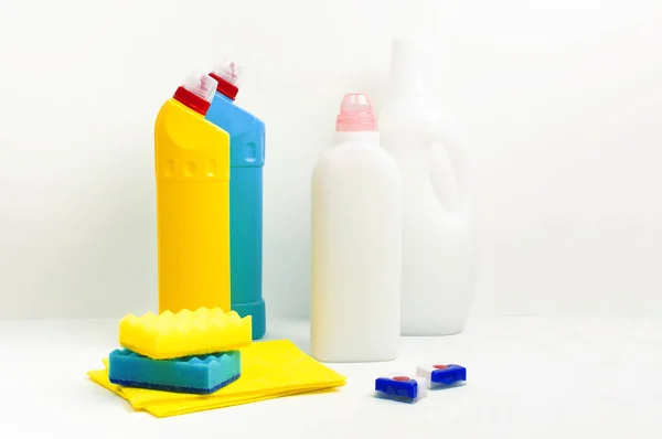 Huisschoonmaakconcept. Chemicaliën voor huishoudelijk gebruik, ontsmettingsmiddel, bleekmiddel, antibacteriële gel, wasverzachter, rubberen handschoenen, spons, lompen, vaatwastabletten op lichte ondergrond Flat lay Schoonmaakaccessoires — Stockfoto