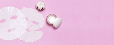 Kumaş yüz maskesi, pembe arka planda pamuk çiçekler. Doğal kozmetik, yüz bakımı, spa, yüz kremi, kadın güzellik aksesuarları. Düz görünüm kopyalama alanı yatıyordu. Kozmetik maketi.