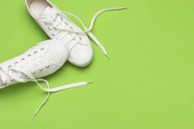 Yeşil arka planda beyaz kadın moda ayakkabıları. Düz görünüm kopyalama alanı yatıyordu. Kadın ayakkabıları. Şık beyaz ayakkabılar. Moda blogu ya da dergi konsepti. Minimalist ayakkabı arkaplanı, spor ayakkabıları.