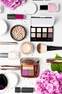 Dekoratif kozmetik maskara tozu ruj göz farı allık makyaj fırçası pembe ortanca çiçekler ışık arka plan üst görünümü Düz konfeti yıldız konfeti seti. Güzellik blogger kavramı. Moda arka plan.