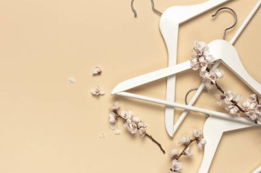 Yaratıcı bahar satışı konsepti. Beyaz ahşap askılar ve bej arka planda kayısı çiçekleri düz bir zemin üzerinde yatıyordu. Moda bahar indirimi mağaza tanıtım tasarımı minimalizmi..