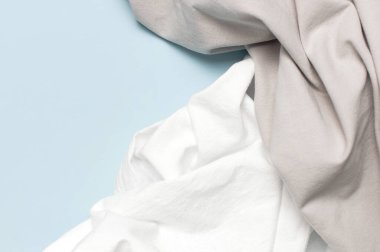 Hassas mavi arka plan manzaralı beyaz ve gri buruşuk doğal pamuk kumaş ve fotokopi alanı. Doğal keten arka plan. Eko tekstil. Beyaz kumaş dokusu. Kumaş arkaplan.