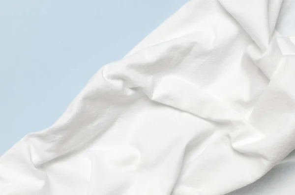 白色皱皱的天然棉织物在精致的蓝色背景上 顶部的视野平坦 有复制的空间 天然亚麻布背景 生态纺织品 白色面料质地 面料背景 — 图库照片