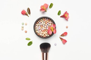 Profesyonel makyaj fırçaları toz allık topları açık arkaplan üzerinde pembe bahar çiçekleri düz üst görünüm fotokopi alanı yatıyordu. Güzellik malzemesi, makyaj, kadın aksesuarı, moda. Makyaj seti.