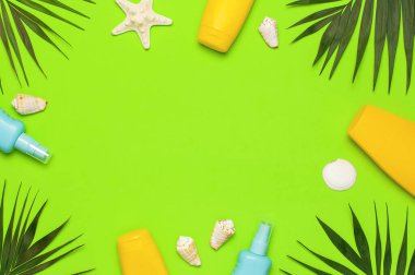 Güneş koruması Yaz tatili konsepti Sarı mavi güneş kremi şişeleri tropikal palmiye yaprakları yeşil arka planda deniz yıldızları düz görünüm fotokopi alanı yatıyordu. Yaz kozmetikleri.