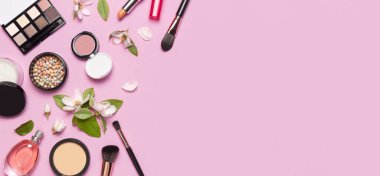 Dekoratif kozmetik maskara pudrası ruj göz farı, makyaj fırçası parfümü pembe arka planda bahar dalları, düz zemin. Güzellik blogcusu kavramı. Moda arkaplanı.