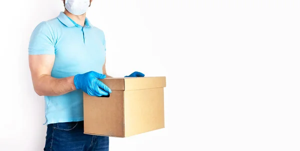 2019 Ncov检疫期间交付货物的概念 戴着医疗面罩 戴着蓝色手套 留着胡子的年轻人手里拿着白底纸盒 无接触式传送病毒保护 — 图库照片