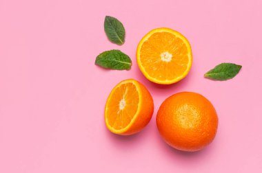 Meyve, yaratıcı yaz konsepti. Taze sulu ve dilimlenmiş portakal, pembe arka planda nane yaprakları. Üst görünüm kopyalama alanı düzleştirildi. Citrus meyveleri, C vitamini sanat tasarımı minimalist arka plan..