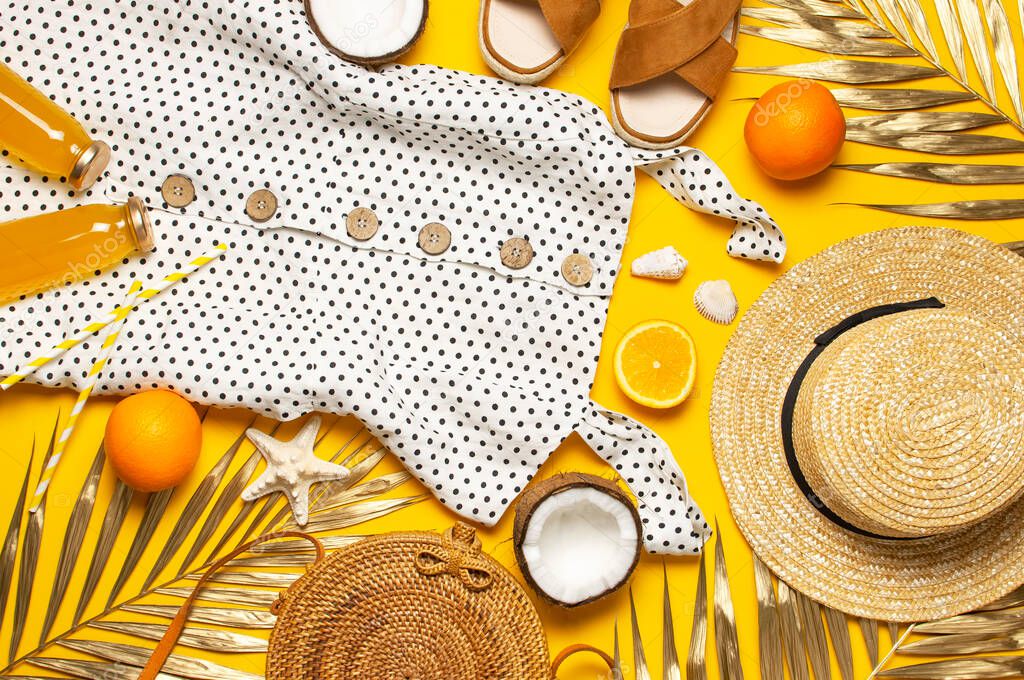 Summer background Beach accessories. Beach wicker straw rattan women's eco bag white dress hat sandals golden tropical leaf coconut orange juice shells starfish on yellow background. Flat lay top view.