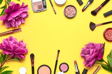 Profesyonel makyaj fırçaları, pudra, göz farı, allık, sarı arka planda ruj kremi düz görünüm fotokopi alanı yatıyordu. Güzellik ürünleri kadın aksesuarları. Farklı fırçalar Kozmetik makyaj seti.