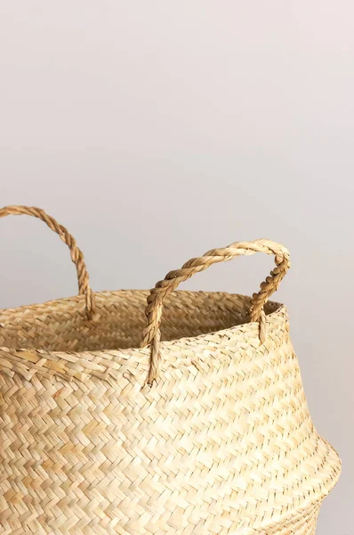 Empty straw wicker basket on a gray background. Fashionable bamboo basket, stylish interior item, eco design, handmade. Natural decor of the interior, home. Natural eco materials, storage basket.