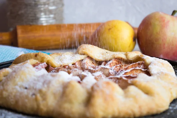 Een koekje met een appel op welke suiker poeder wordt gegoten — Stockfoto