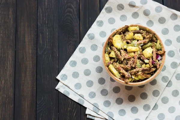 Salada bávara com carne defumada em um fundo escuro — Fotografia de Stock