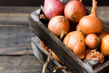 Karanlık bir arka plan üzerinde bir ahşap kutu soğan