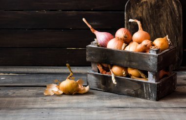 Karanlık bir arka plan üzerinde bir ahşap kutu soğan