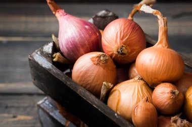 Karanlık bir arka plan üzerinde bir ahşap kutu soğan