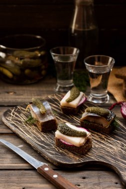 Pastırma ve karanlık bir arka plan üzerine votka için çerez olarak ringa balığı ile Mini sandviç