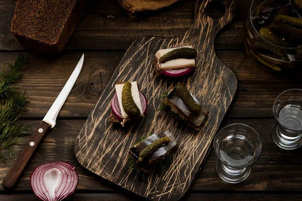 Mini sándwiches con tocino y arenque como aperitivo al vodka sobre un fondo oscuro — Foto de Stock