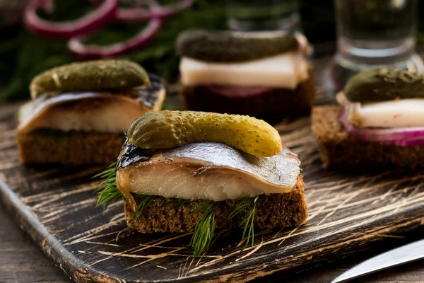 Pastırma ve karanlık bir arka plan üzerine votka için çerez olarak ringa balığı ile Mini sandviç