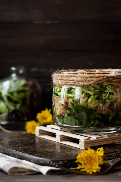 Салат из проросшей сои и листьев одуванчика в банке — стоковое фото