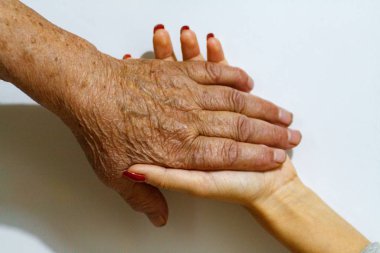 Yaşlı bir kadın büyükanne ve genç bir kız el ele tutuşuyor. Gençlerden ve çocuklardan yaşlılara destek. Emekli yaşlılarla ilgilenmek.