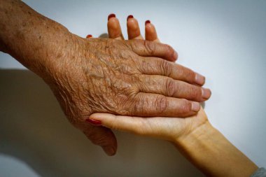 Yaşlı bir kadın büyükanne ve genç bir kız el ele tutuşuyor. Gençlerden ve çocuklardan yaşlılara destek. Emekli yaşlılarla ilgilenmek.