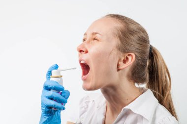 Genç ve çekici bir doktor. Boğazına sprey sıkılmış.